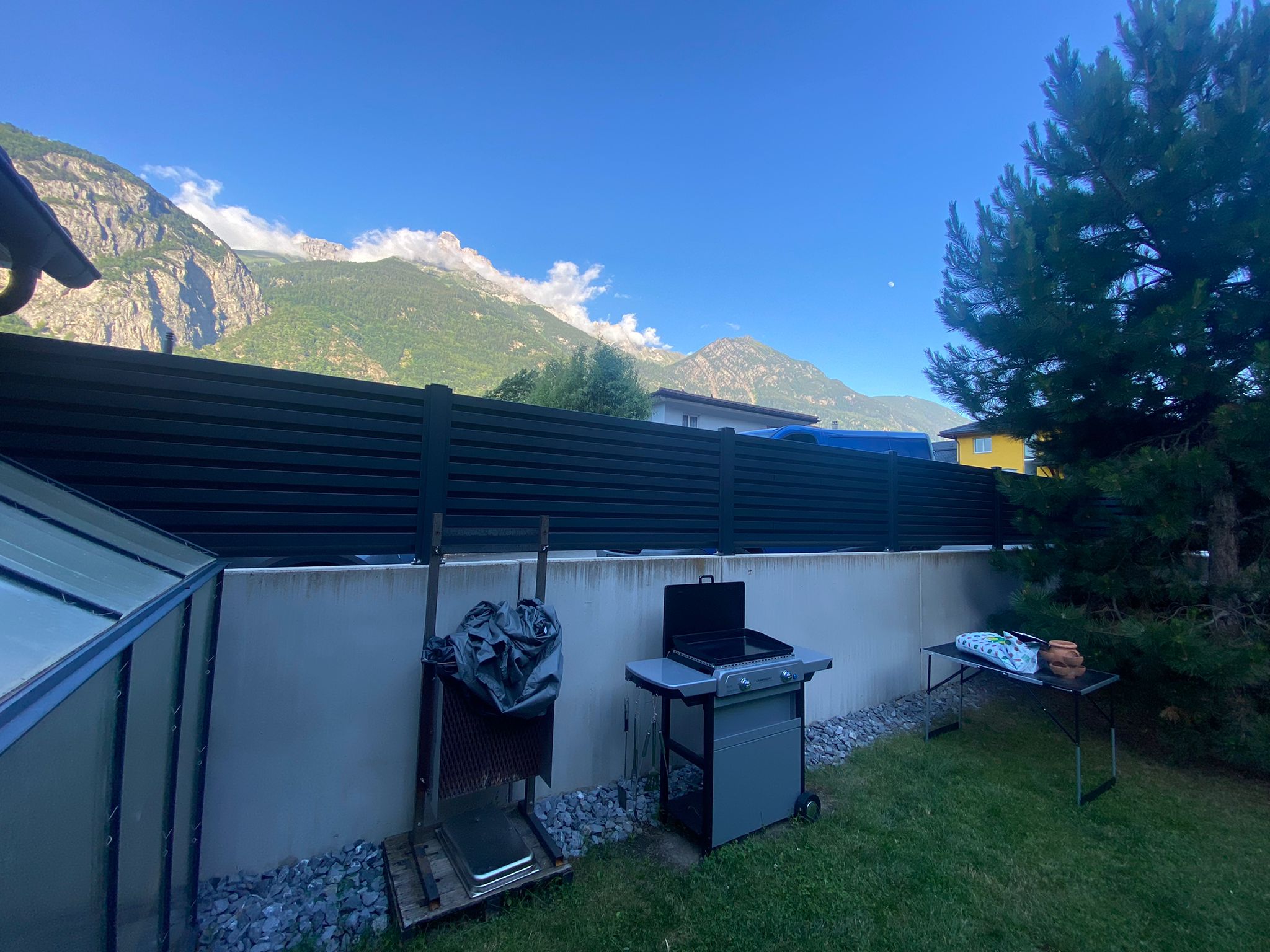 Portail extérieur sécurisé avec clôture, vue jardin suisse et montagnes.