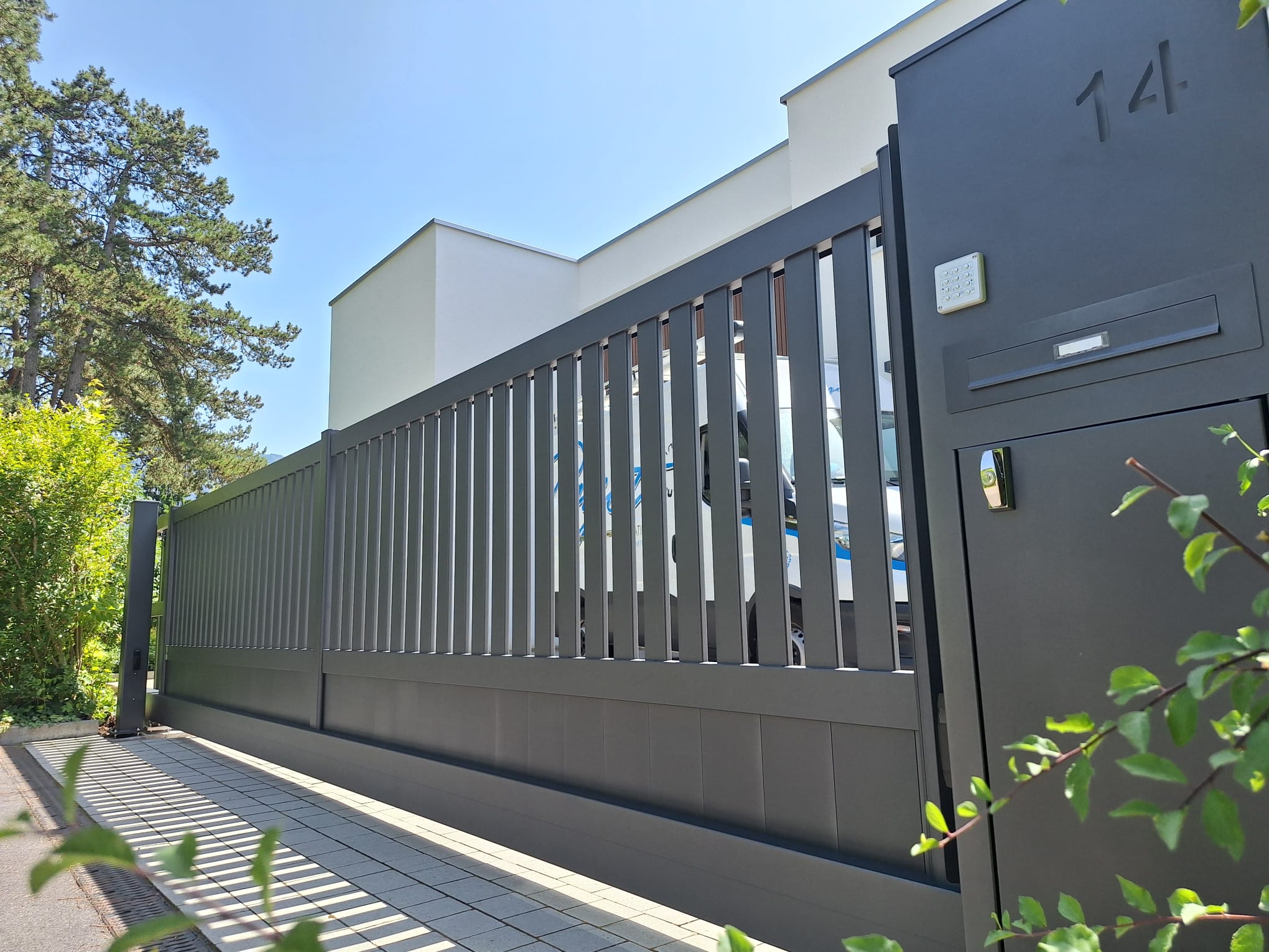 Portail coulissant métal noir moderne devant maison suisse, installation professionnelle.
