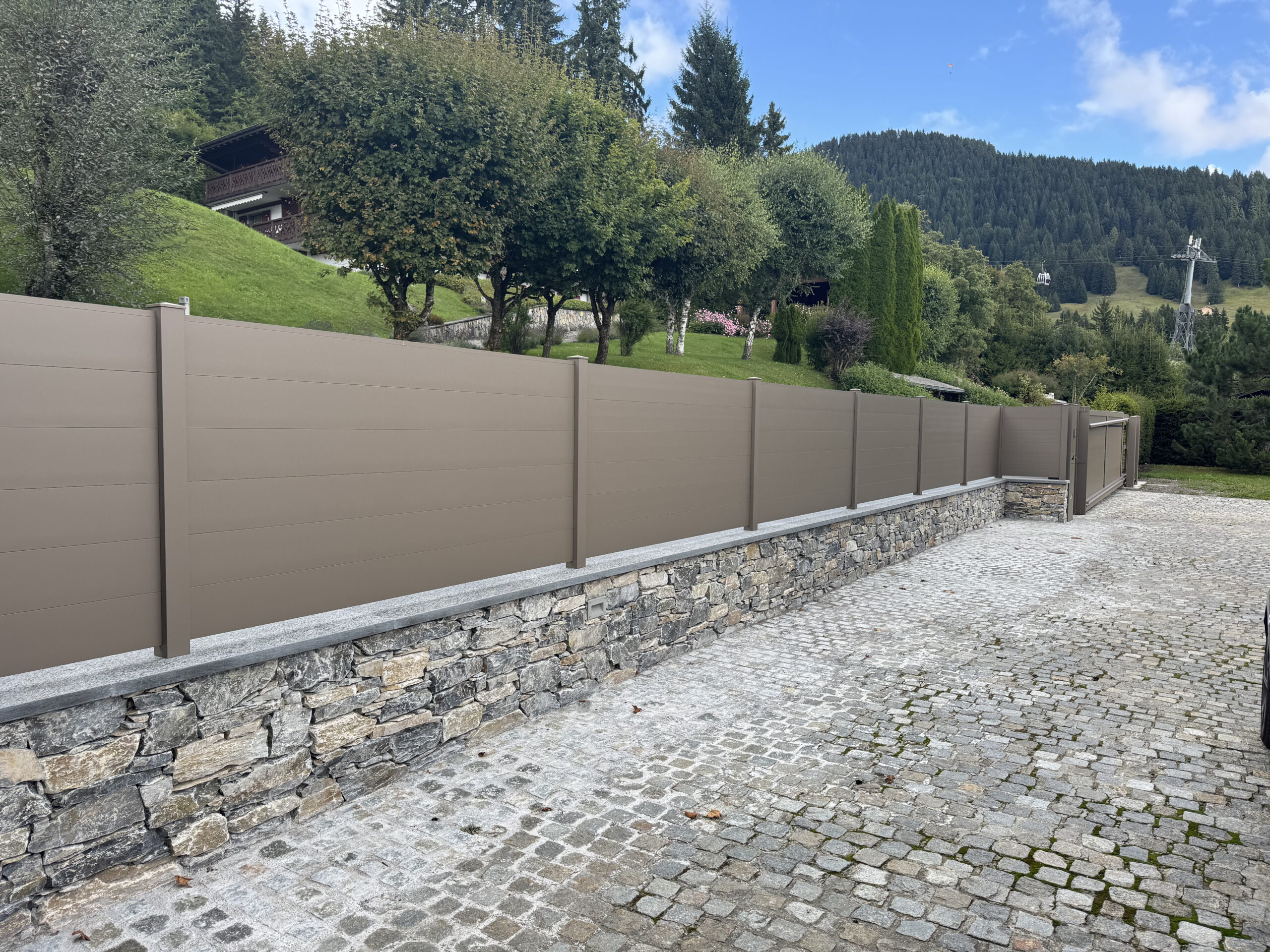 Clôture beige moderne sur mur en pierre, installation experte portail extérieur Suisse.
