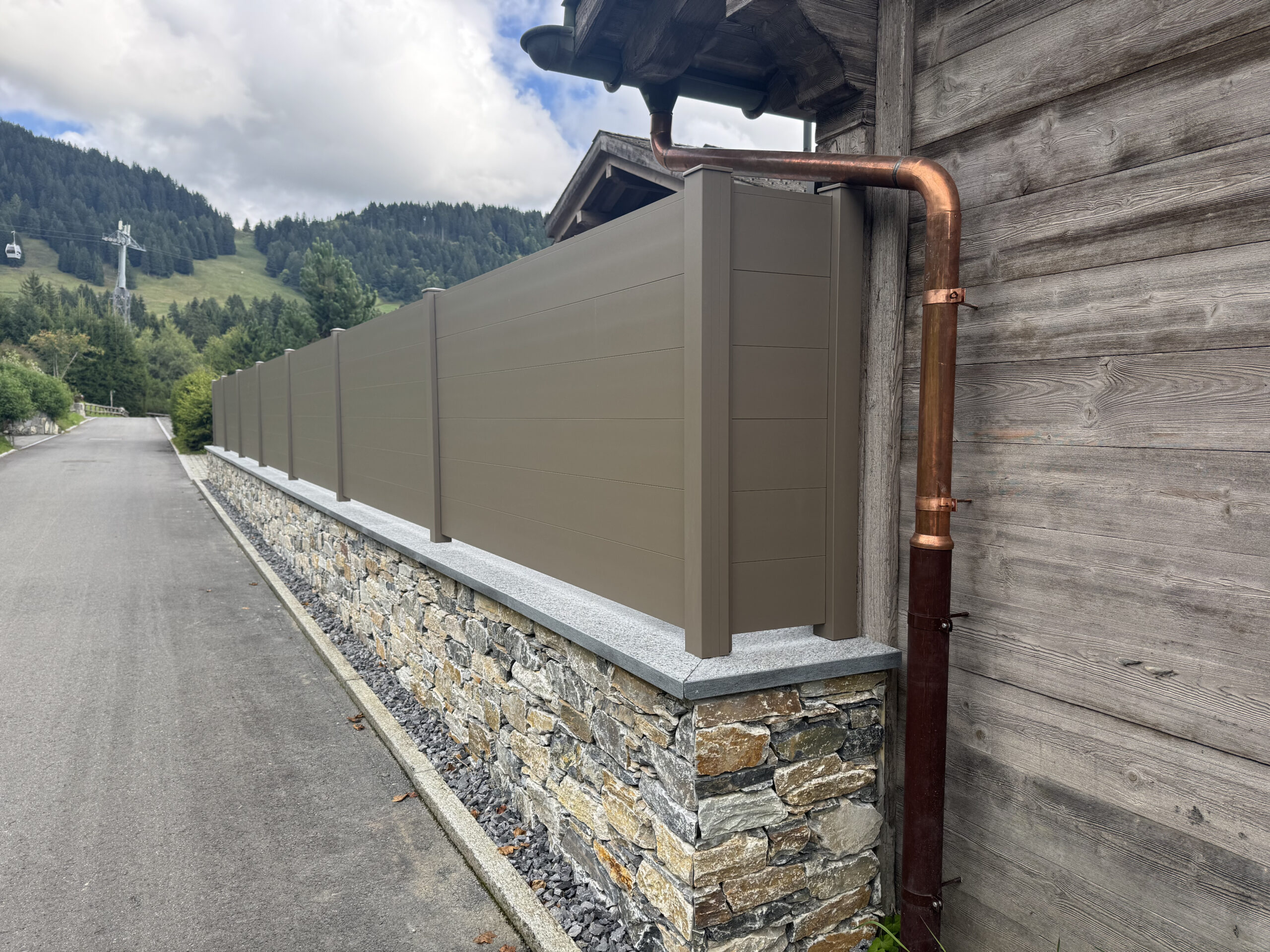 Clôture extérieure en bois installée sur muret, façade suisse professionnelle.