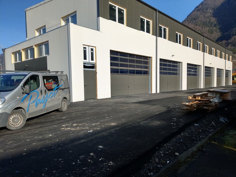 Bâtiment moderne avec portes de garage grises, utilitaire Puyjal-spécialiste suisse portails, clôtures, motorisations extérieures.