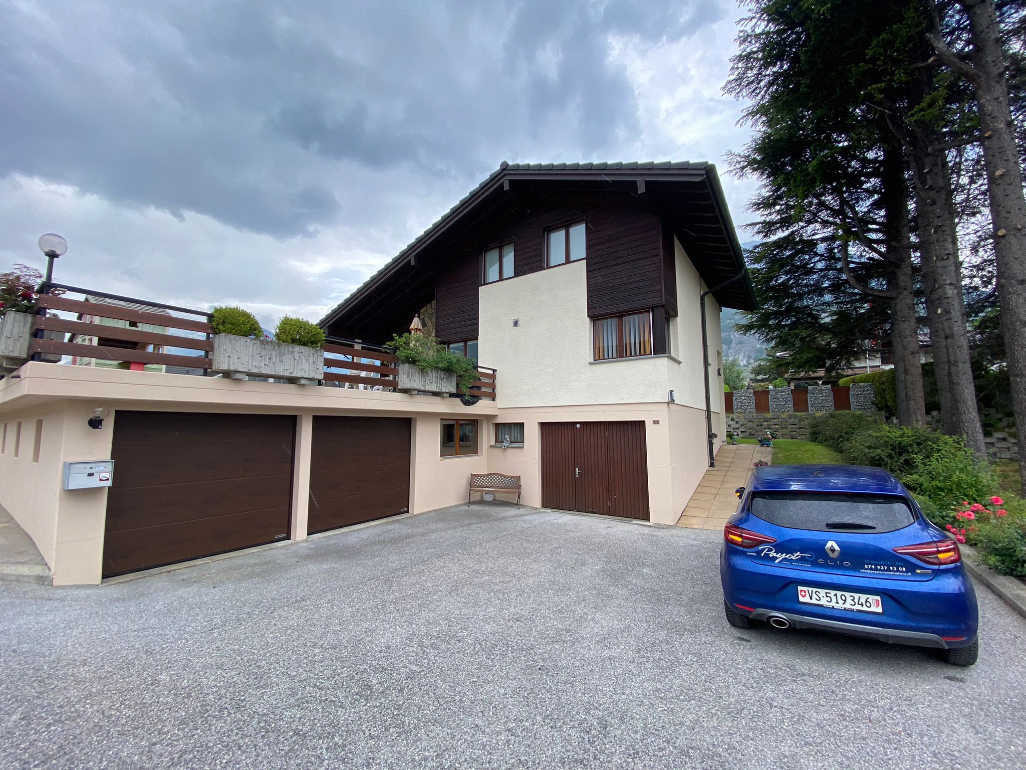 Maison moderne suisse avec trois portes de garage, portail extérieur, installation professionnelle.