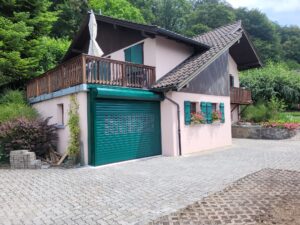 Maison rose, portail extérieur, porte de garage verte : installation experte suisse.