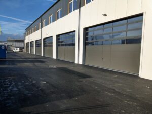 Bâtiment industriel moderne avec portes de garage grises, idéal installation portail extérieur Suisse.